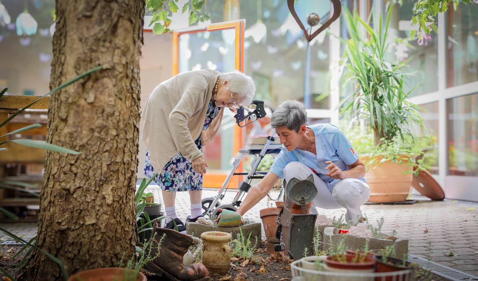 Eine Seniorin und eine Pflegerin bei der Gartenarbeit im Haus Rosenberg.