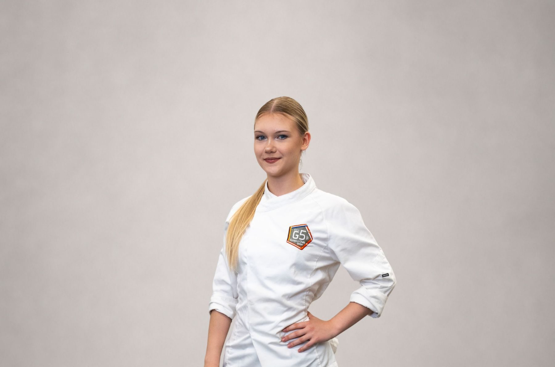 Koch-Lehrling Anastasia posiert in Kochjacke und schwarzer Hose.